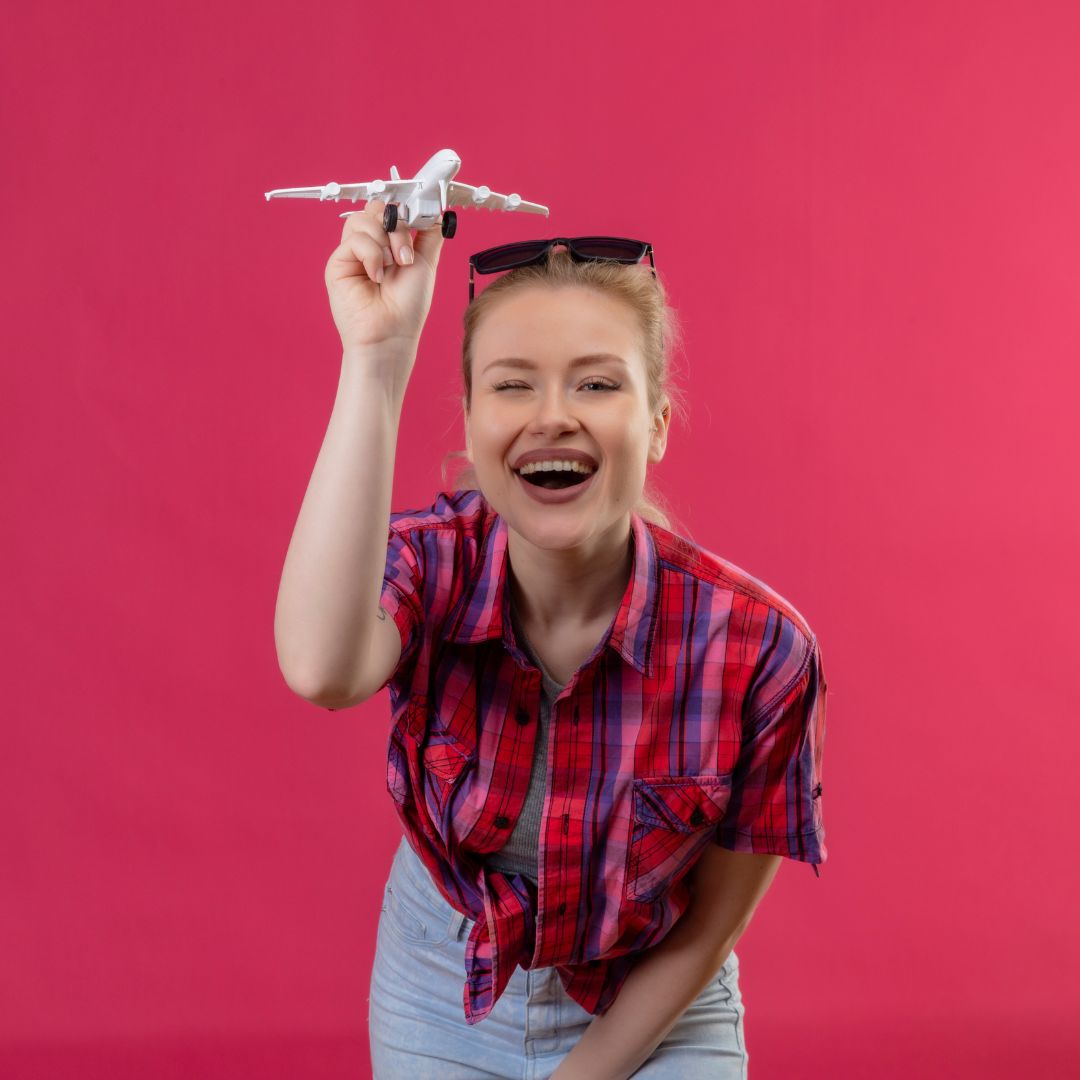 Smiling traveler holding a miniature airplane, ready to explore worldwide private jet charter destinations.